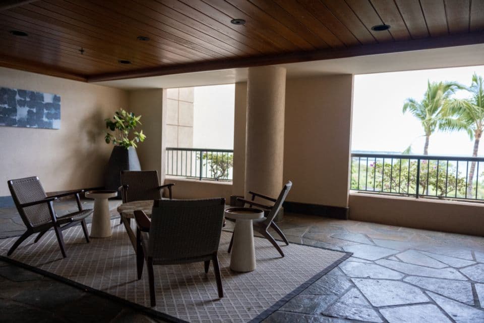 A shaded terrace lounge with palm trees beyond the railing