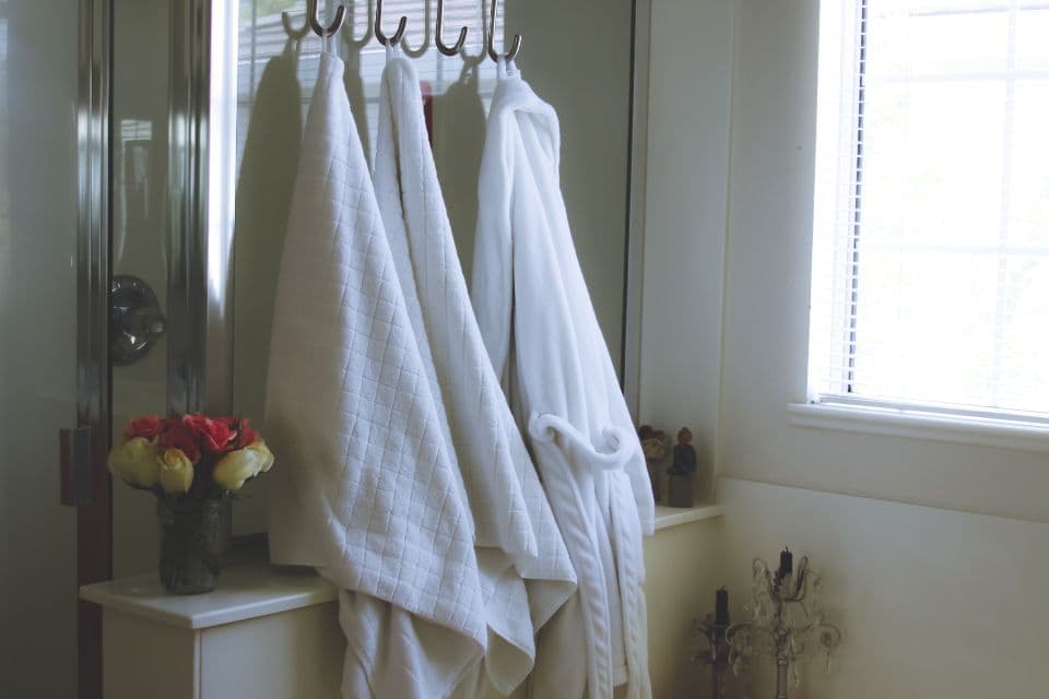 Fresh white bathrobes and towels by a window